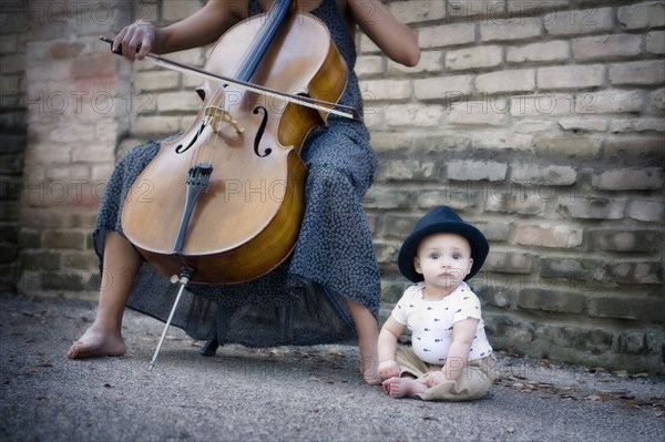 Mixed race musician playing cello with baby daughter