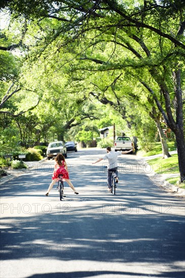 Caucasian children riding bicycles on suburban neighborhood street