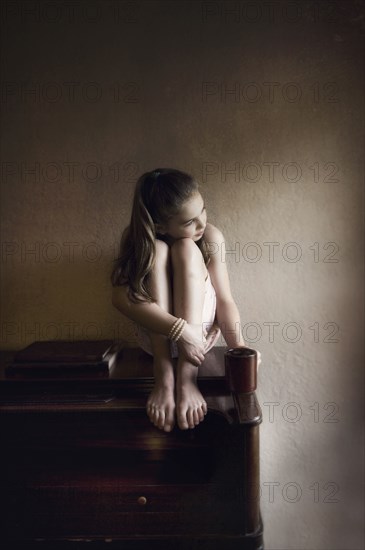 Caucasian girl sitting on dresser