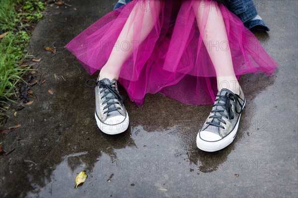 Caucasian girl wearing sneakers and tutu in puddle