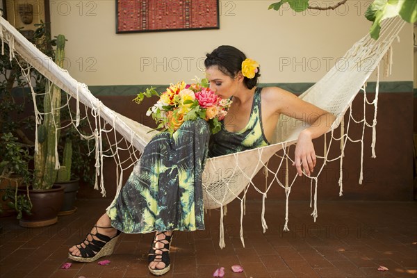 Woman smelling bouquet of flowers in hammock