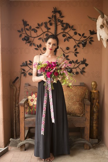 Woman in evening gown carrying bouquet of flowers