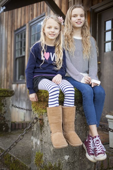 Sisters sitting on mossy pedestal