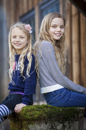 Sisters sitting on mossy pedestal