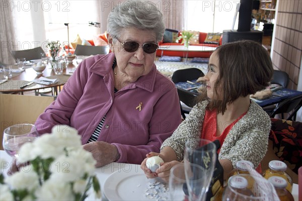 Grandmother and granddaughter cooking at table