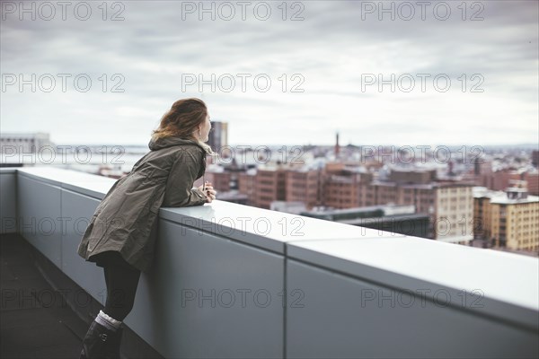 Caucasian woman on urban rooftop admiring cityscape