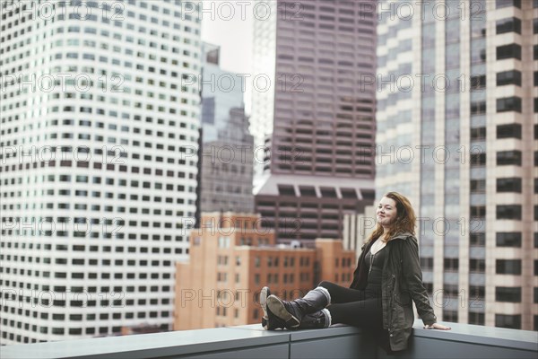 Caucasian woman on urban rooftop admiring cityscape