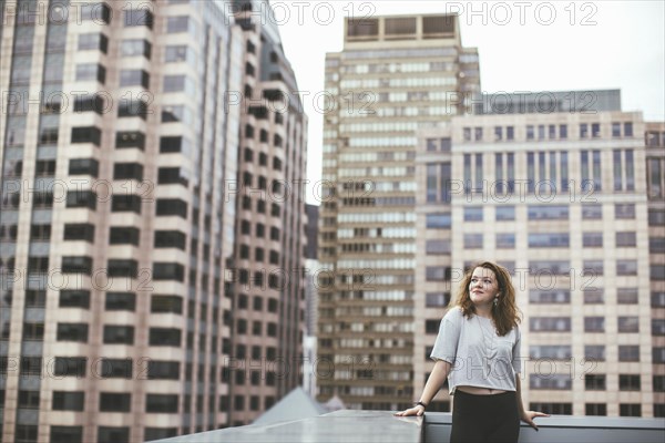 Caucasian woman on urban rooftop admiring cityscape