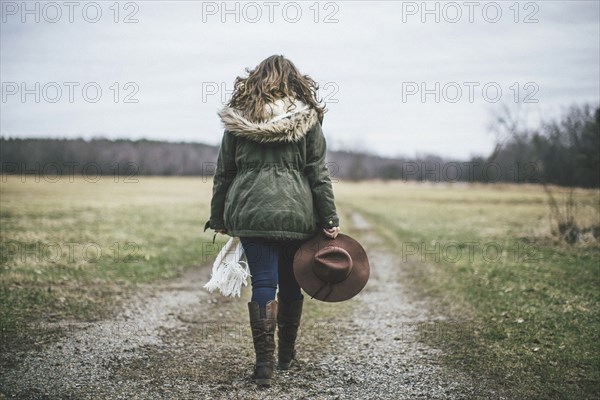 Caucasian woman walking on dirt path in rural field