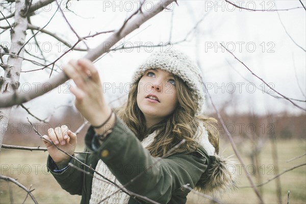 Caucasian woman examining tree branches