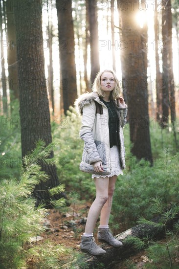 Caucasian woman standing on tree log in forest