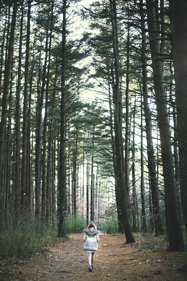 Caucasian woman walking on dirt path in forest