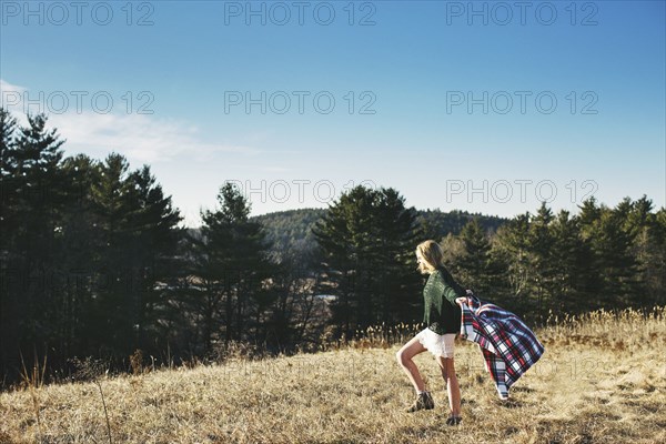 Caucasian woman playing with scarf on rural hilltop