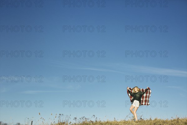 Caucasian woman playing with scarf on hilltop