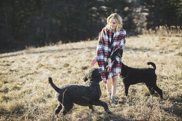 Caucasian woman playing with dogs in rural field