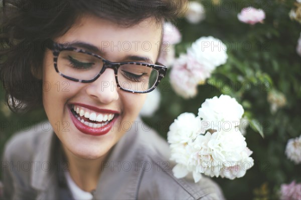 Caucasian woman admiring flowers on shrub