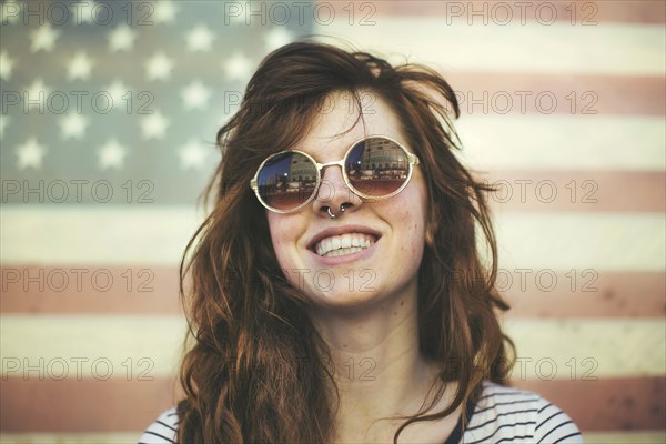 Caucasian woman wearing sunglasses at American flag