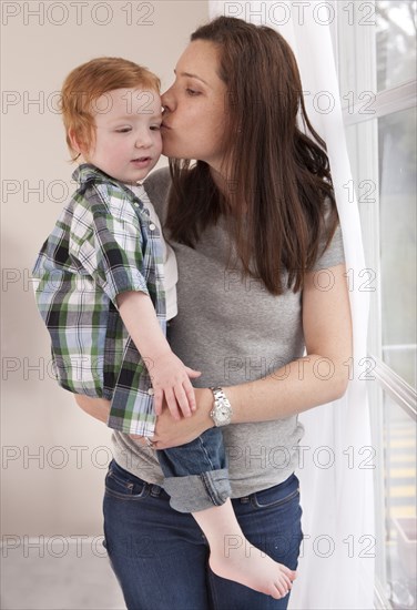 Mother kissing son near window