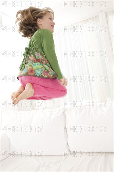 Caucasian girl jumping on sofa in living room