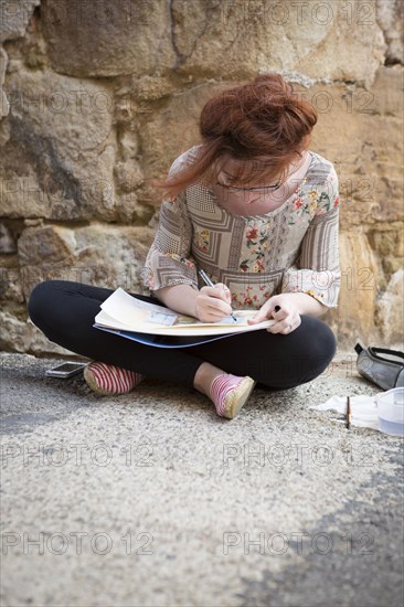 Caucasian girl drawing on concrete ground