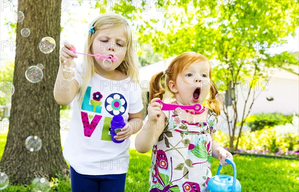 Caucasian girls blowing bubbles in background