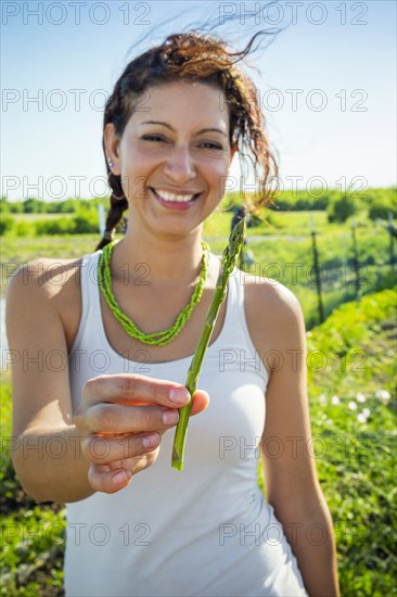 Hispanic woman holding asparagus in garden