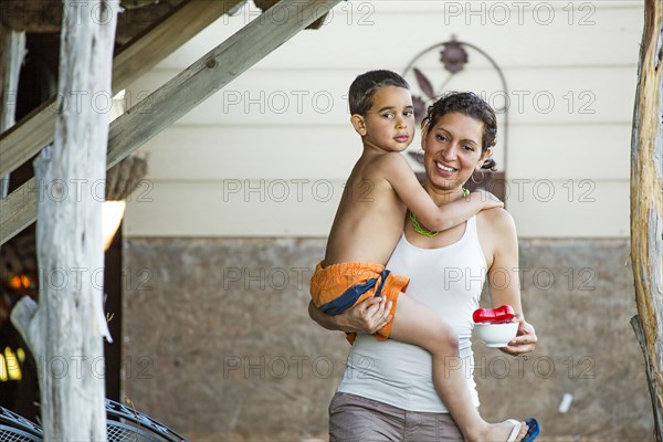 Mother carrying son in backyard