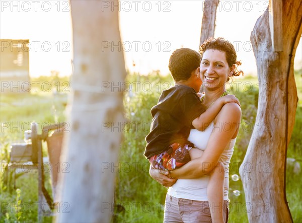 Hispanic mother carrying son in garden