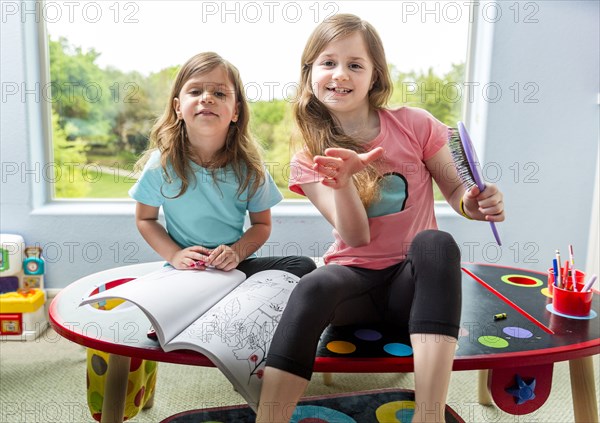 Caucasian sisters drawing at table in playroom