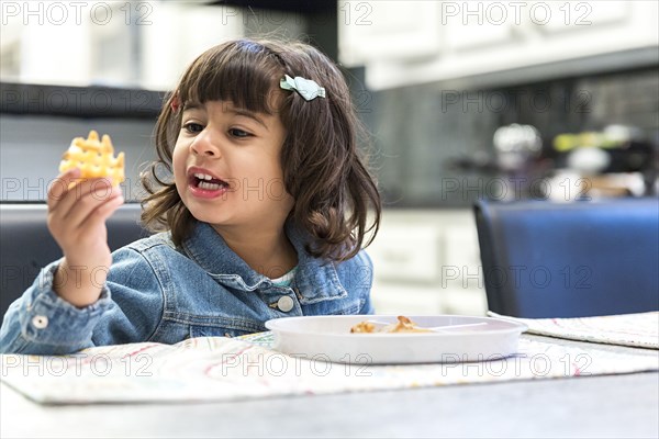 Girl eating waffle fries in kitchen