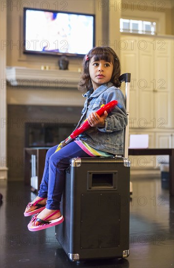 Girl playing toy guitar on amplifier in living room