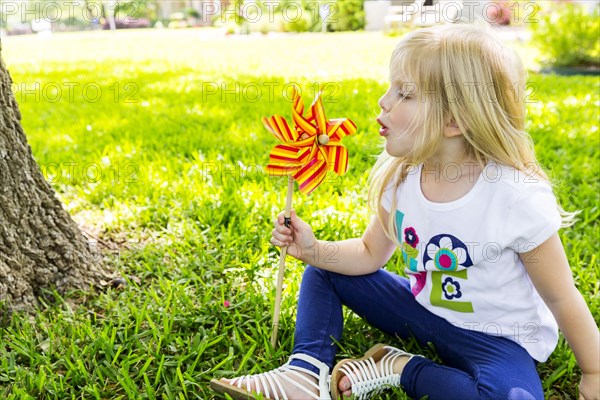 Caucasian girl playing with pinwheel in backyard