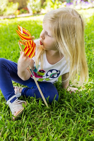 Caucasian girl playing with pinwheel in backyard