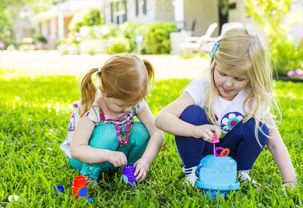 Caucasian sisters blowing bubbles in backyard