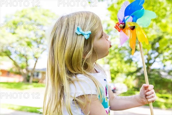 Caucasian girl playing with pinwheel in backyard