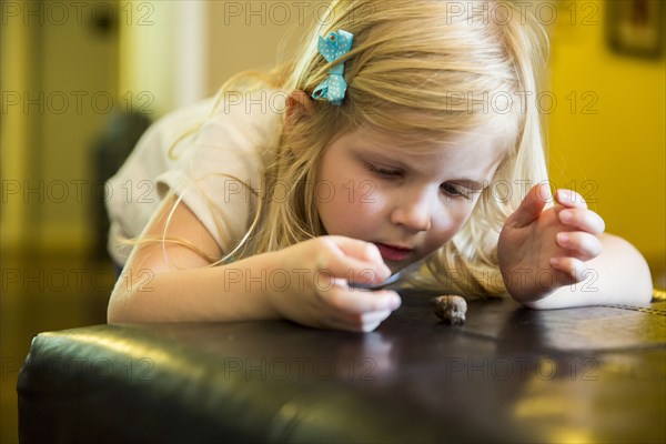 Caucasian girl playing with snail on ottoman