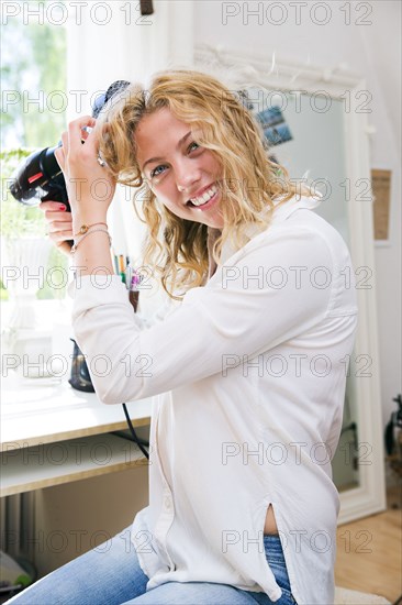 Woman drying her hair in bedroom