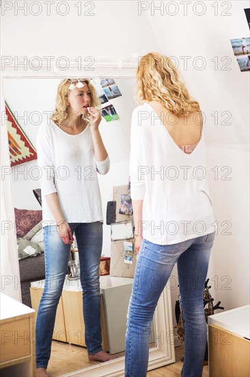 Woman applying lipstick in mirror