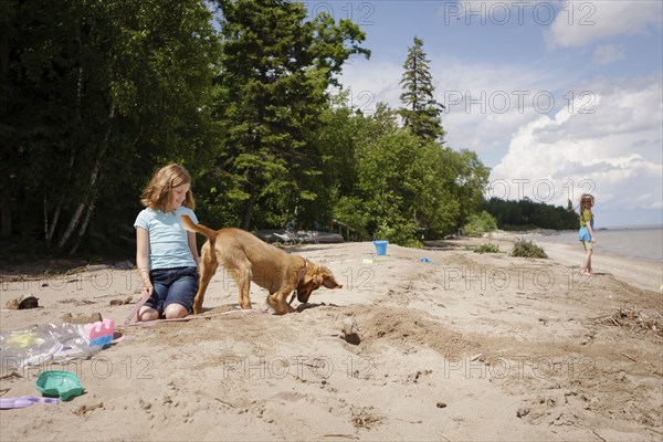 Caucasian girl and puppy playing on beach