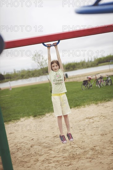 Caucasian girl hanging from structure in playground