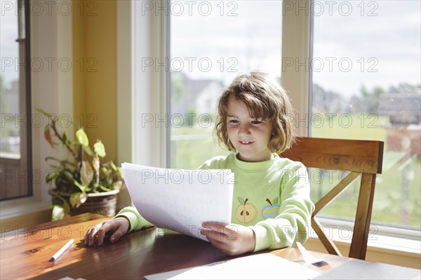 Caucasian girl reading papers at table