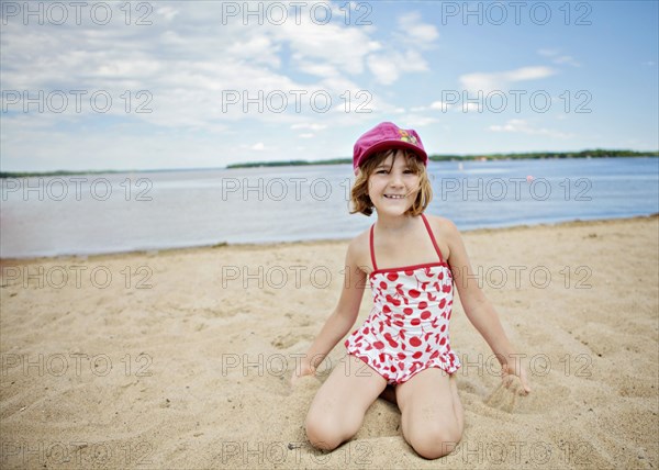 Caucasian girl kneeling on beach