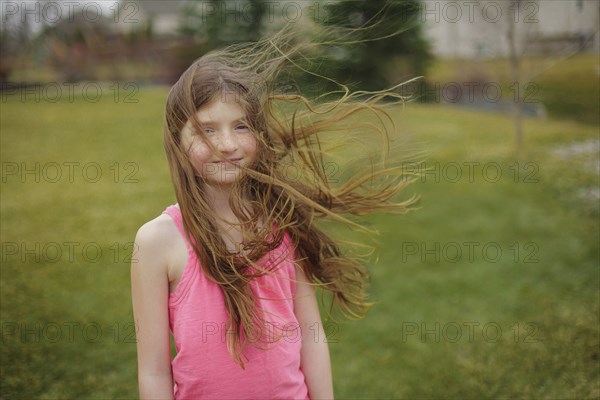 Hair of Caucasian girl blowing in wind in backyard
