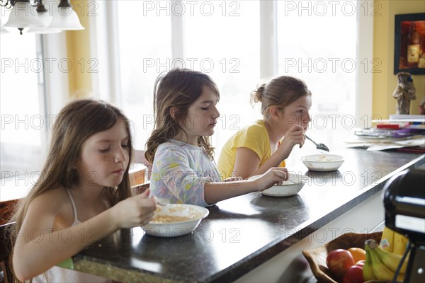 Caucasian sisters eating breakfast in kitchen