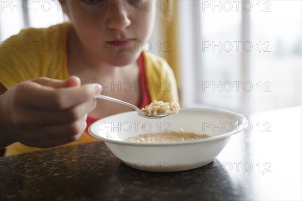 Caucasian girl eating breakfast at table