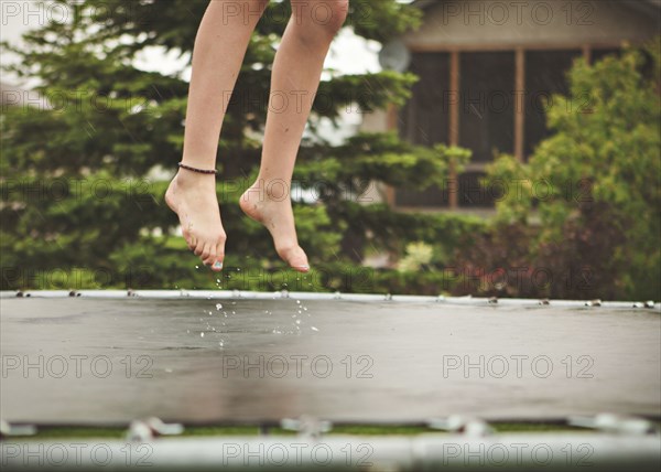 Caucasian girl jumping on wet trampoline
