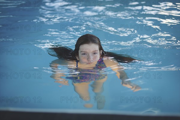 Caucasian girl floating in swimming pool