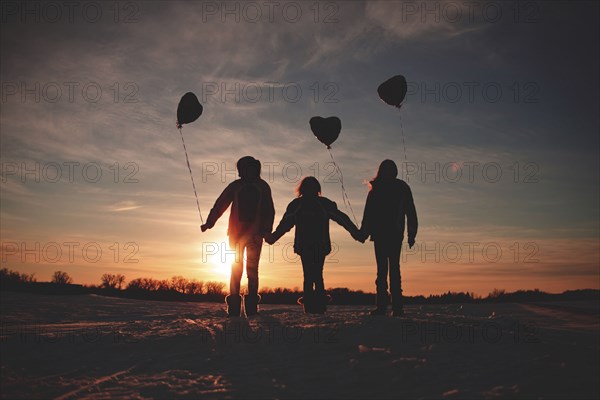 Caucasian girls walking with balloons at sunset