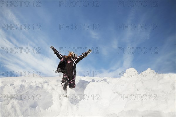 Caucasian girl jumping on snowy hillside