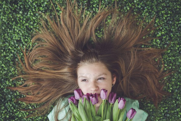 Caucasian girl with tulips laying in grass